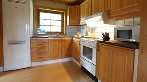 Una cocina con armarios de madera, un refrigerador blanco, una estufa y un microondas.