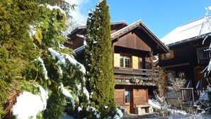 A wooden chalet with a balcony, surrounded by snow-covered trees and a clear blue sky. - old ,small ,typical chalet in the center of a mountain village :Le Grand Bornand (Le Grand Bornand)