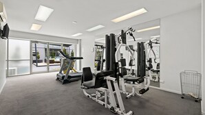 A modern gym with exercise equipment, large windows, and a carpeted floor. - Modern and Spacious Two Bedroom Apartment (Burwood)