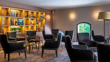 A modern lounge with leather chairs, a bookshelf, and a view of greenery.