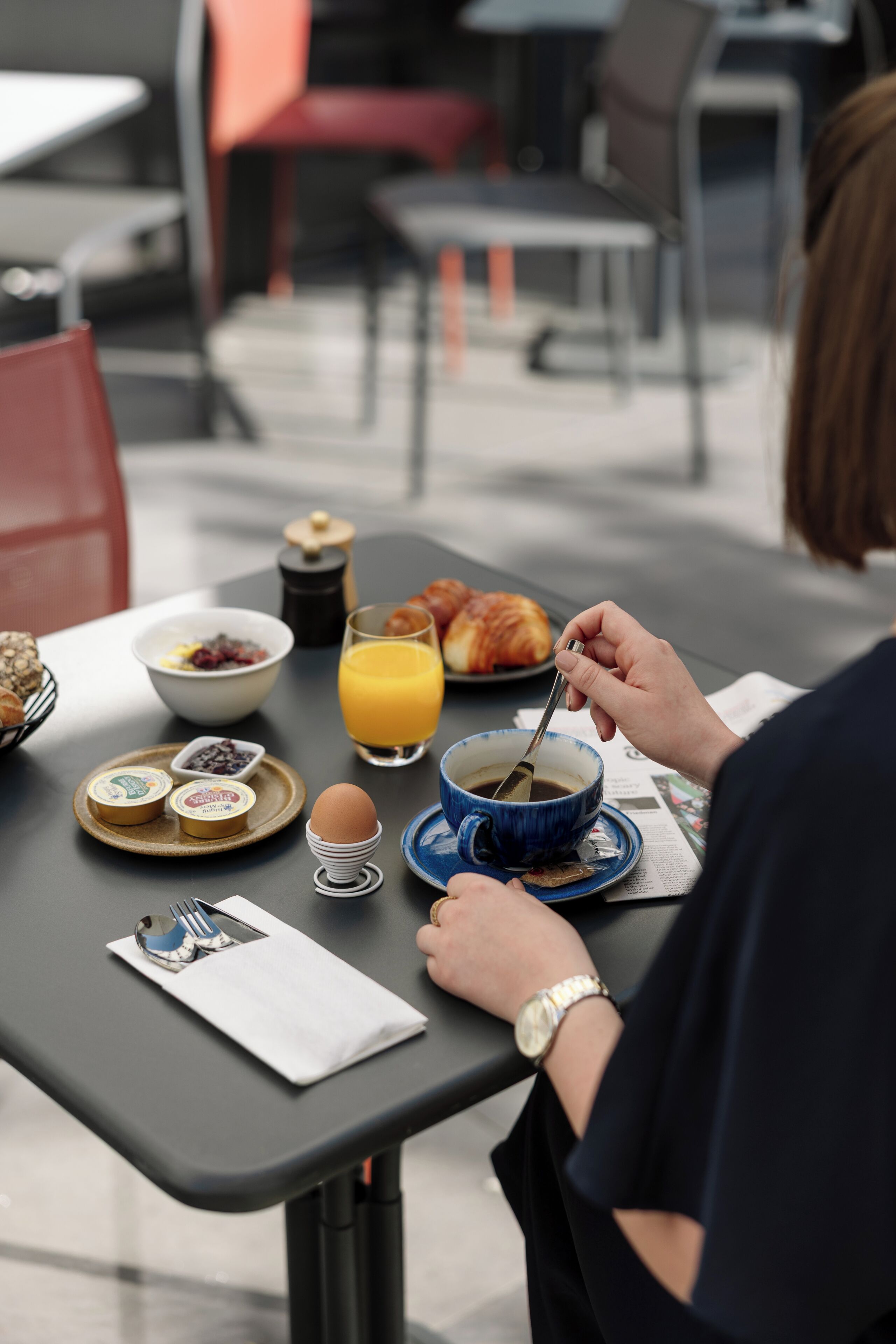 Een ontbijttafel met croissants, een kom cornflakes, een glas sinaasappelsap en een kop koffie.