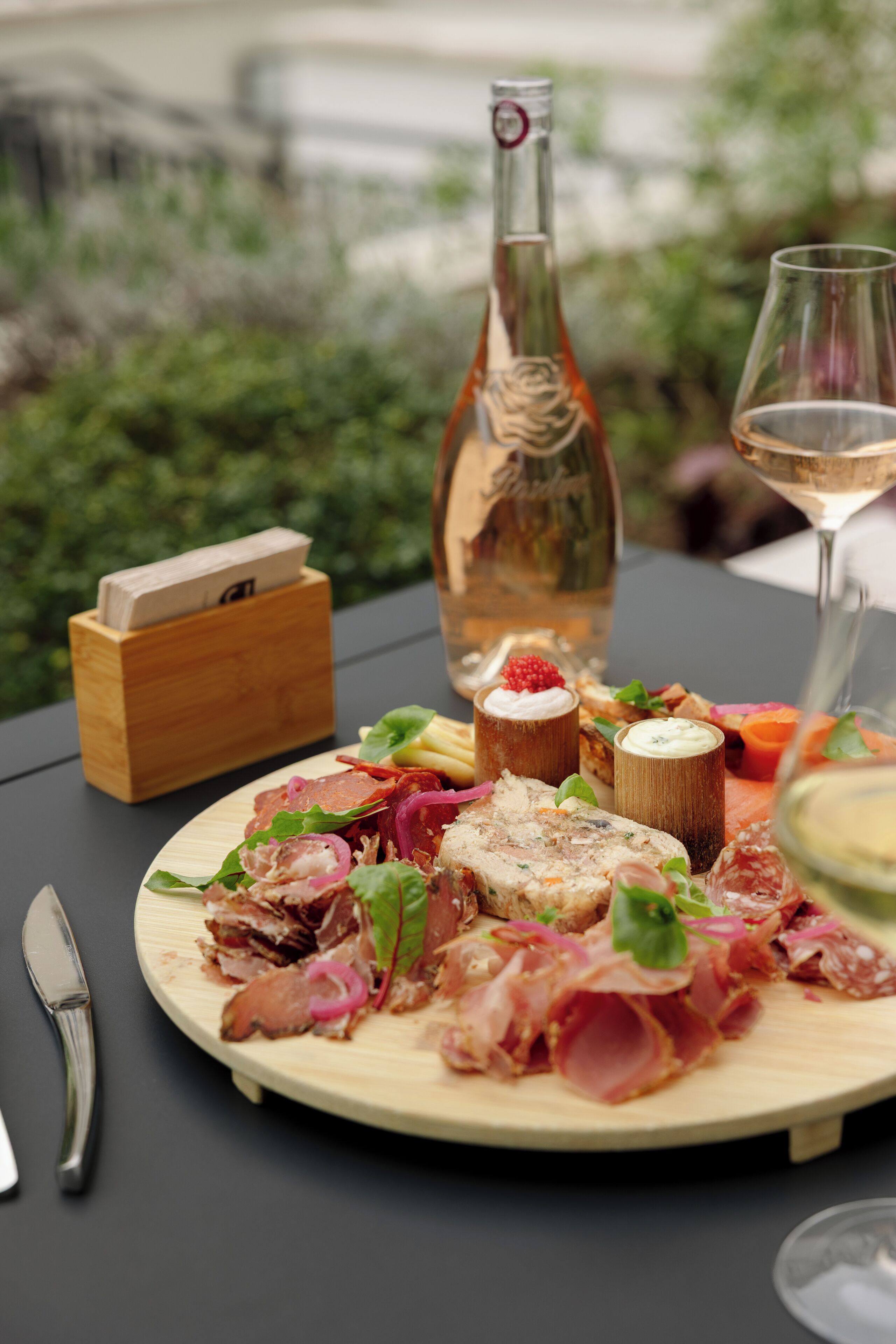 Ein Holztisch mit einem Teller Essen, einer Flasche und einem Weinglas.