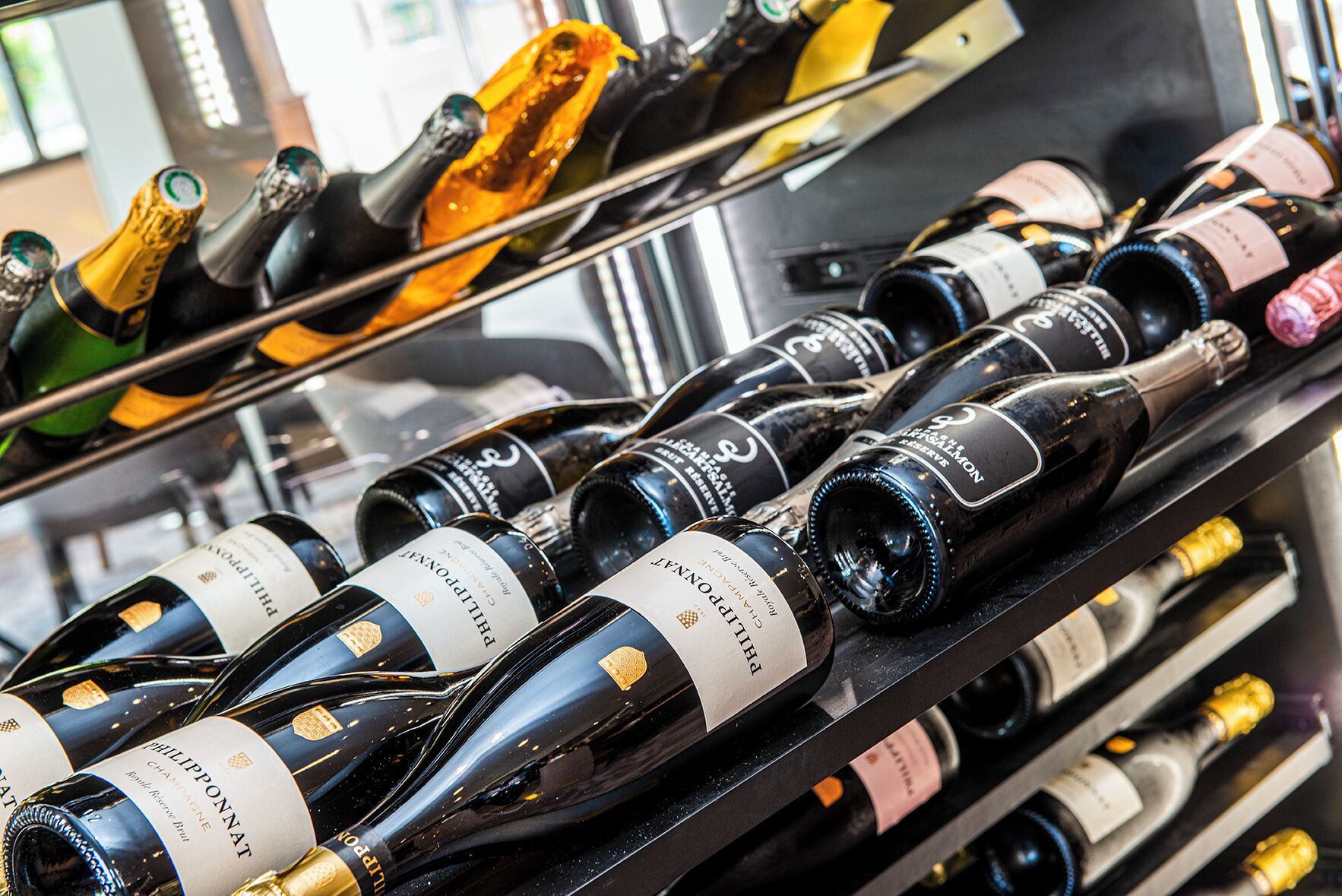 A collection of wine bottles on shelves, likely in a wine shop or restaurant.