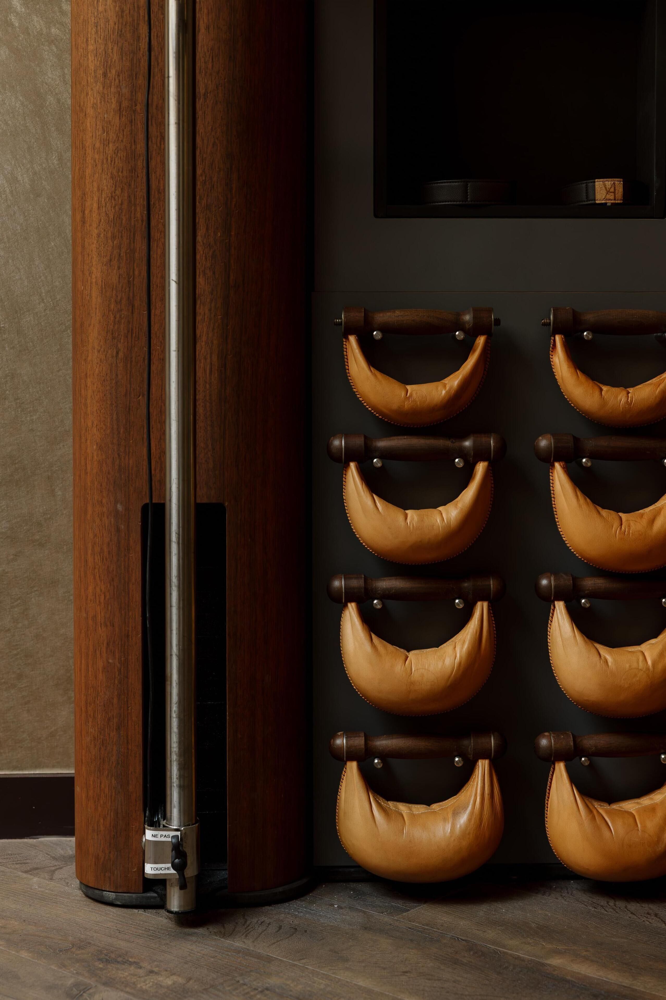 A room with a wooden column, a wall-mounted television, and a series of leather straps.