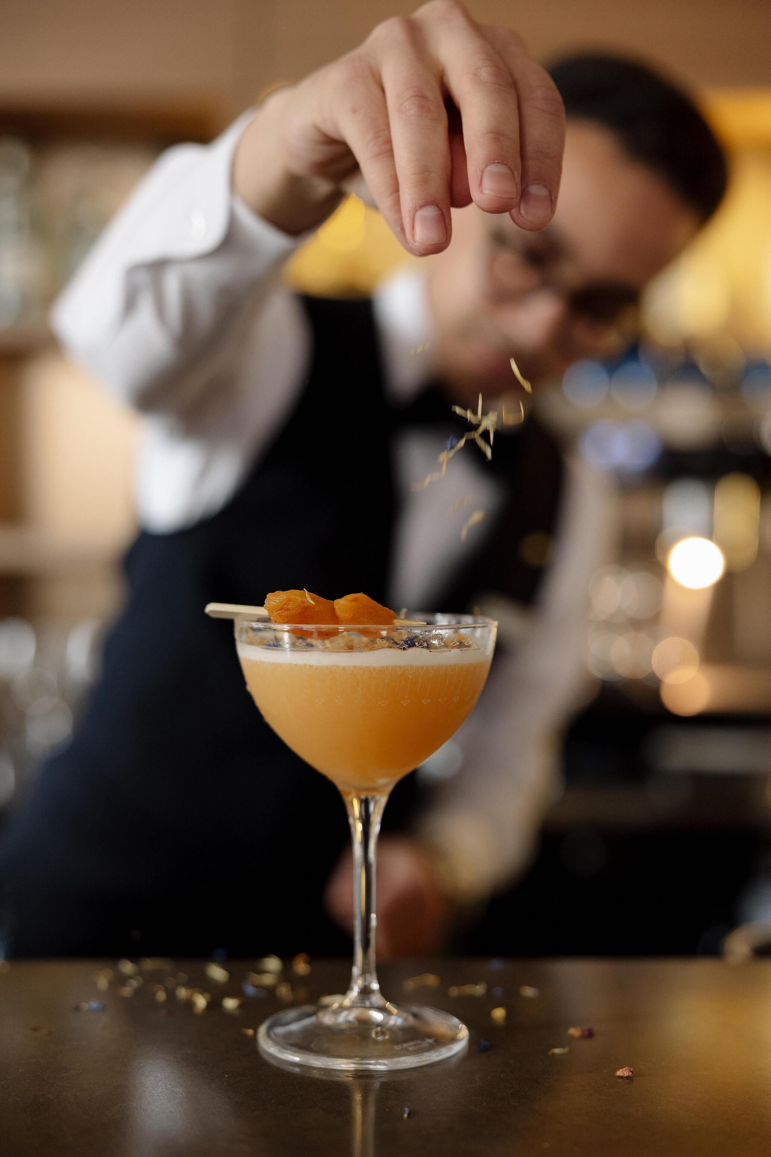 A bartender preparing a cocktail with a garnish.