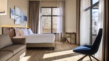 A hotel room with a bed, a sofa, a desk, and a chair.