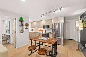 A modern kitchen with stainless steel appliances, a wooden dining table, and a cozy seating area.