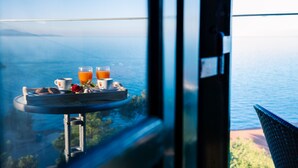 A breakfast tray with orange juice and cookies on a balcony overlooking a body of water. - Potamitis Windmills & Apartments (Zakynthos)