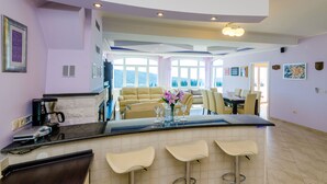 Eine moderne Küche mit Barbereich, einem Essbereich mit einer Couch und Stühlen sowie großen Fenstern mit Blick.