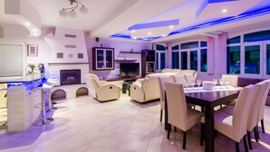 Ein modernes Wohnzimmer mit Fernseher, Sofas und einem Essbereich mit Stühlen und einem Tisch.