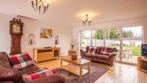 A living room with a brown leather sofa, a wooden coffee table, a wooden cabinet, a clock, and a television on a wooden stand. - *Relocation, Business and Contractor Long Stays! (Oxford)