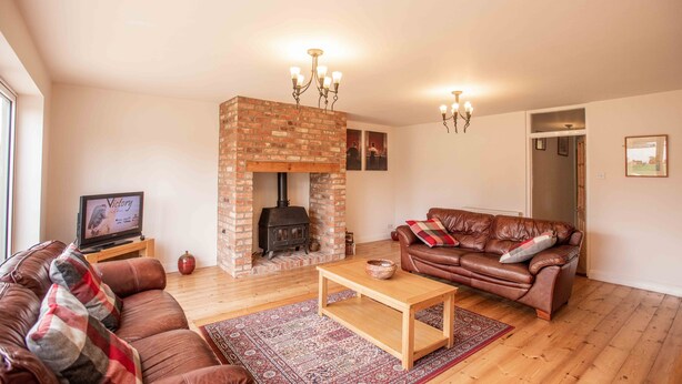 A living room with a brick fireplace, leather sofa, wooden coffee table, and a television on a stand. - *Relocation, Business and Contractor Long Stays! (Oxford)