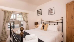 A bedroom with a bed, curtains, a lamp, and framed pictures on the wall. - *Relocation, Business and Contractor Long Stays! (Oxford)