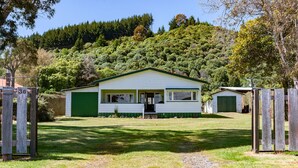 A single-story house with a green garage, a front porch, and a driveway leading to the entrance. - Marina Views - Motuoapa Bach (Motuoapa)