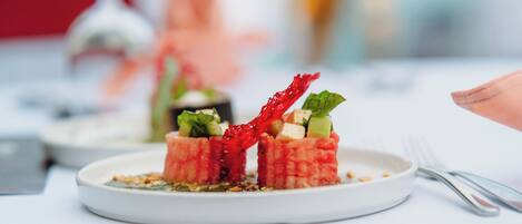 Un plato de comida con un adorno rojo y hojas verdes, sobre un mantel blanco.