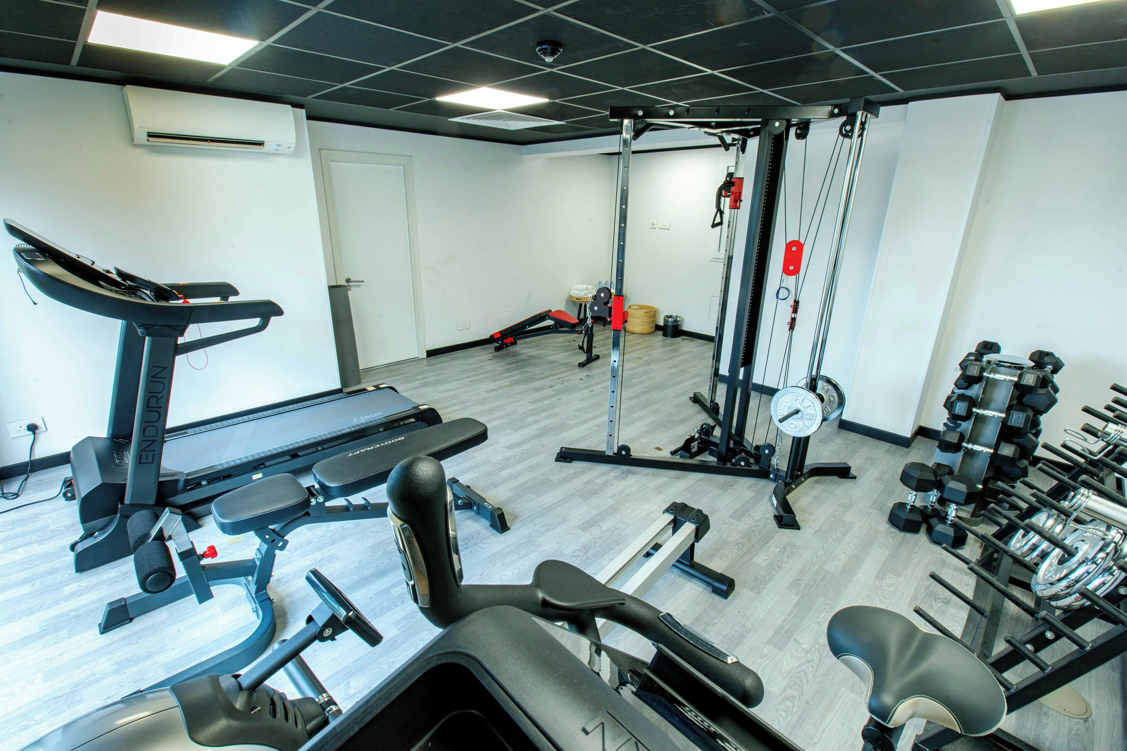 A gym with various exercise equipment including a treadmill, weight bench, and free weights.