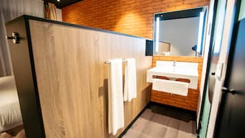 A modern bathroom with a wooden vanity, a large mirror, and a shower enclosure.