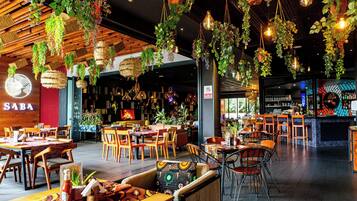 A restaurant interior with hanging plants, wooden furniture, and a bar area.