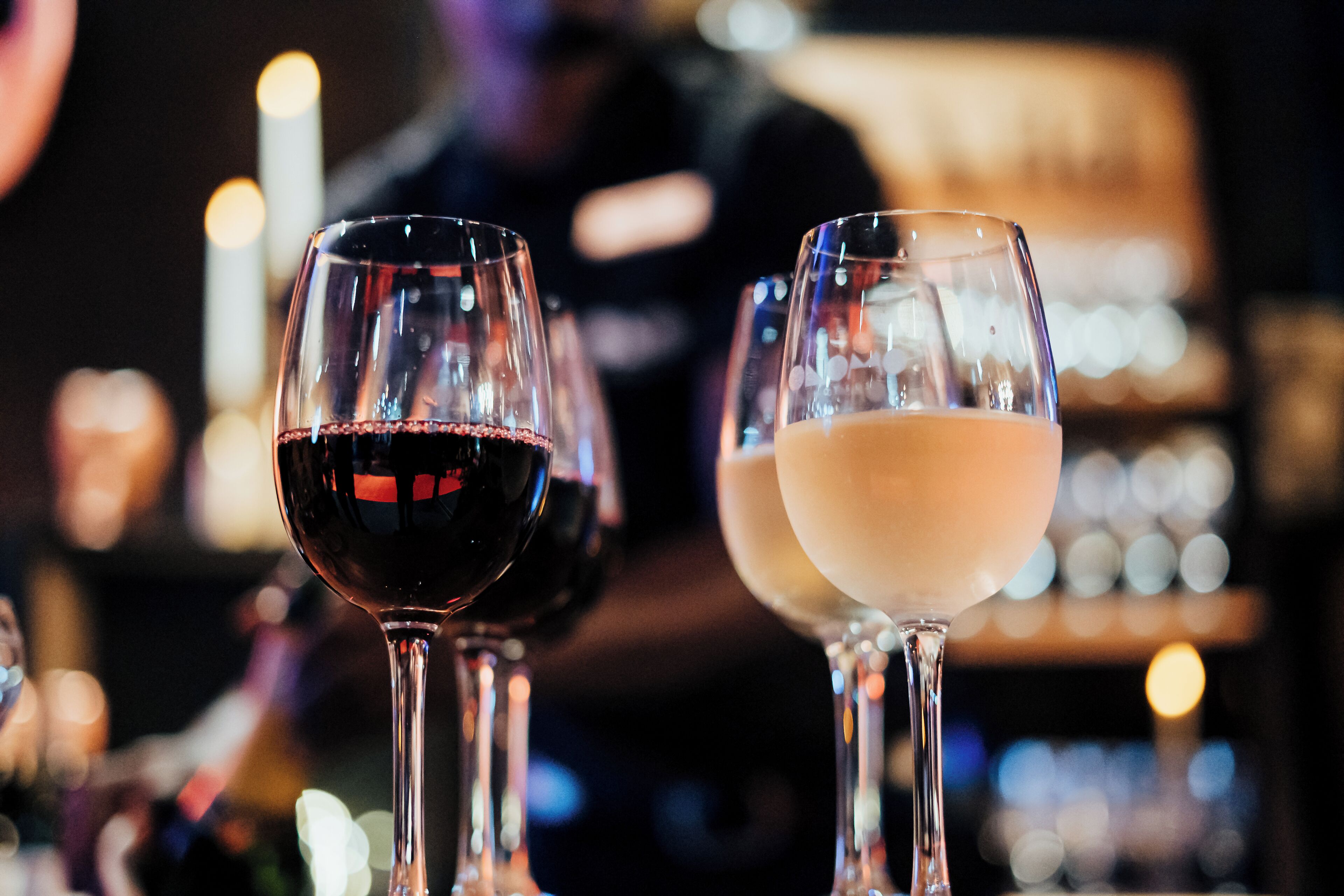 Two glasses of wine, one red and one white, on a bar counter.