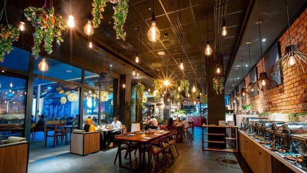 Een restaurant met hangplanten, onbehandelde bakstenen muren en diverse zitmogelijkheden.
