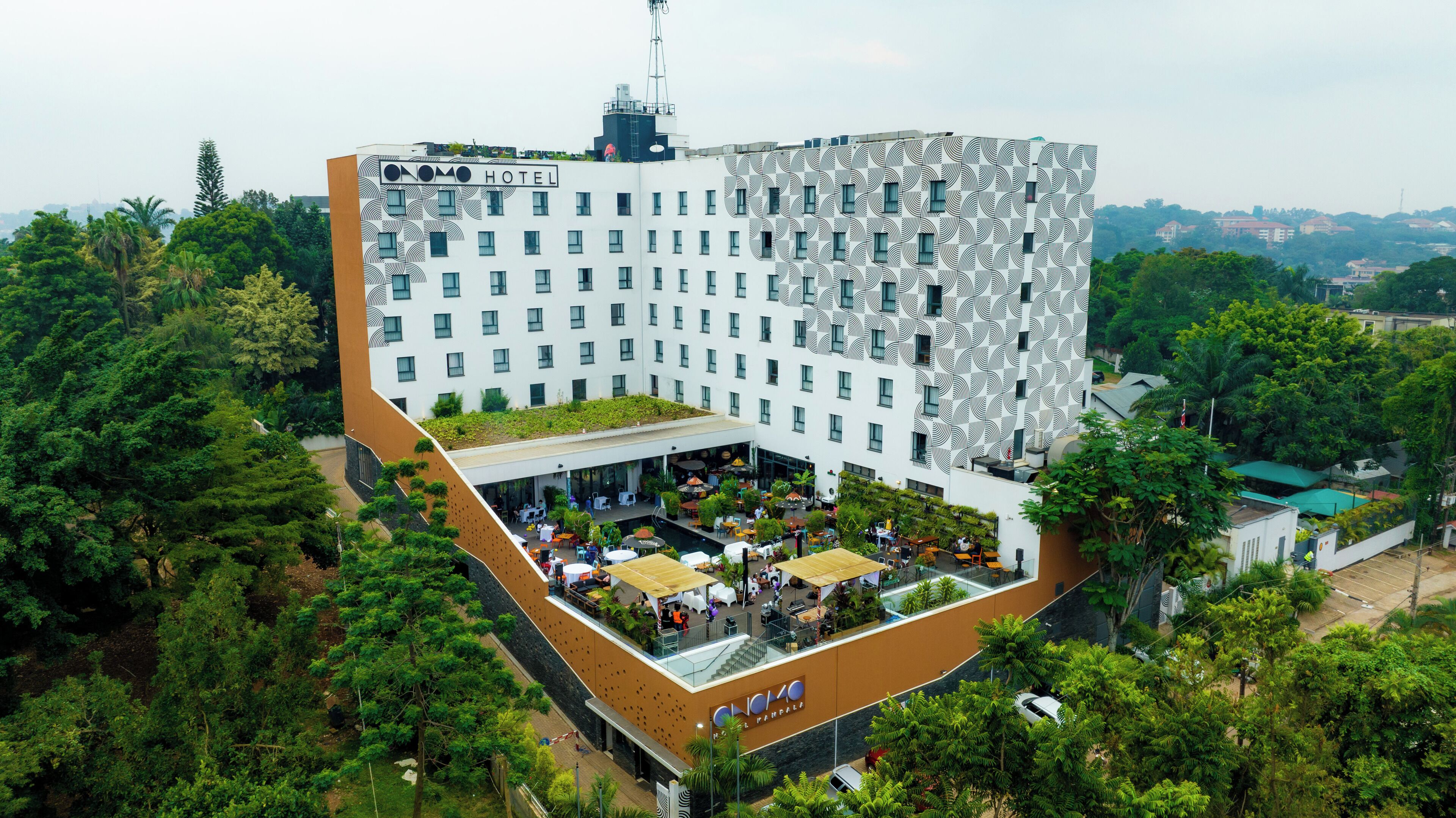 A hotel with a unique geometric facade, a rooftop garden, and an outdoor seating area.