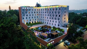 Een hotel met een unieke gevel, meerdere verdiepingen en een rooftopbar met terras.