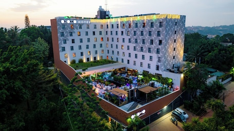 A hotel with a unique facade, multiple floors, and a rooftop bar with outdoor seating.