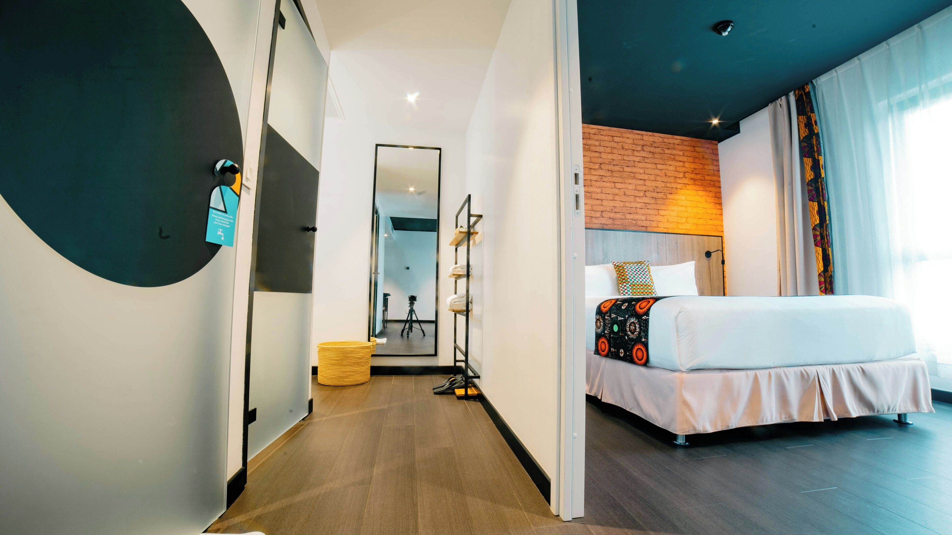 Ein Hotelzimmer mit Bett, Spiegel, Kleiderschrank und einer Kamera-Stativ.