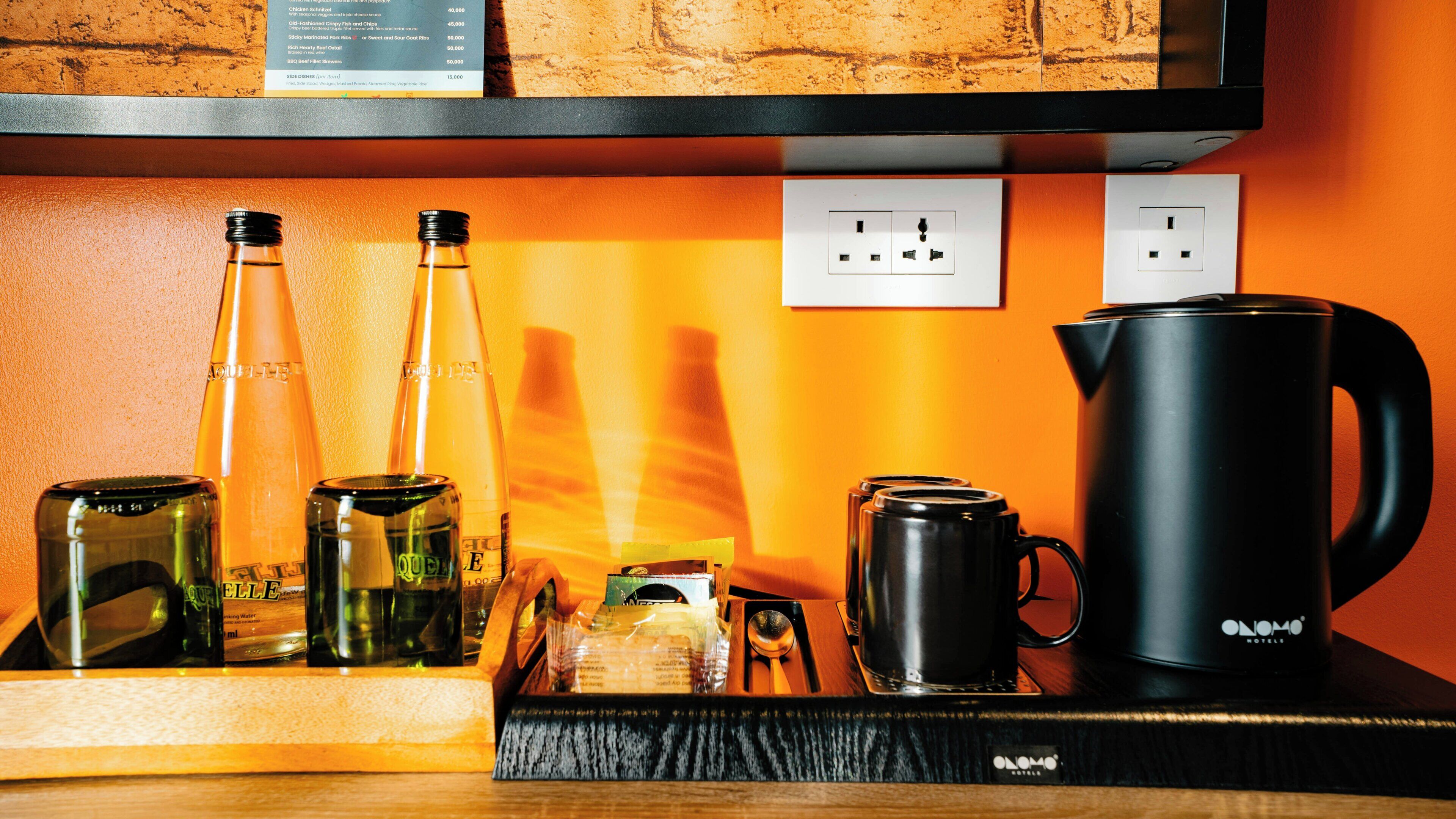 A kitchen counter with various items including bottles, a kettle, and a coffee maker.