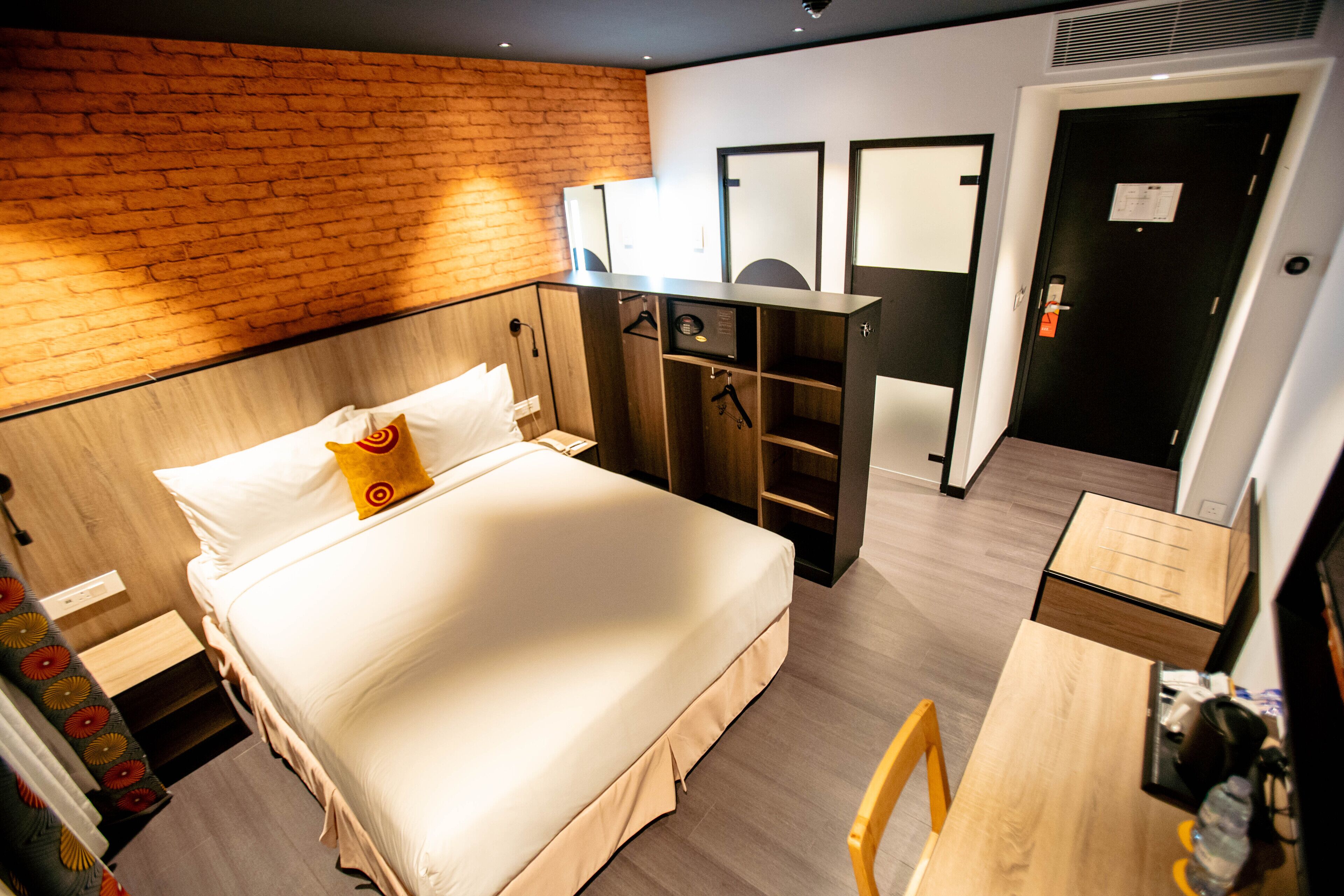 A hotel room with a bed, a desk, a wardrobe, and a mirror.