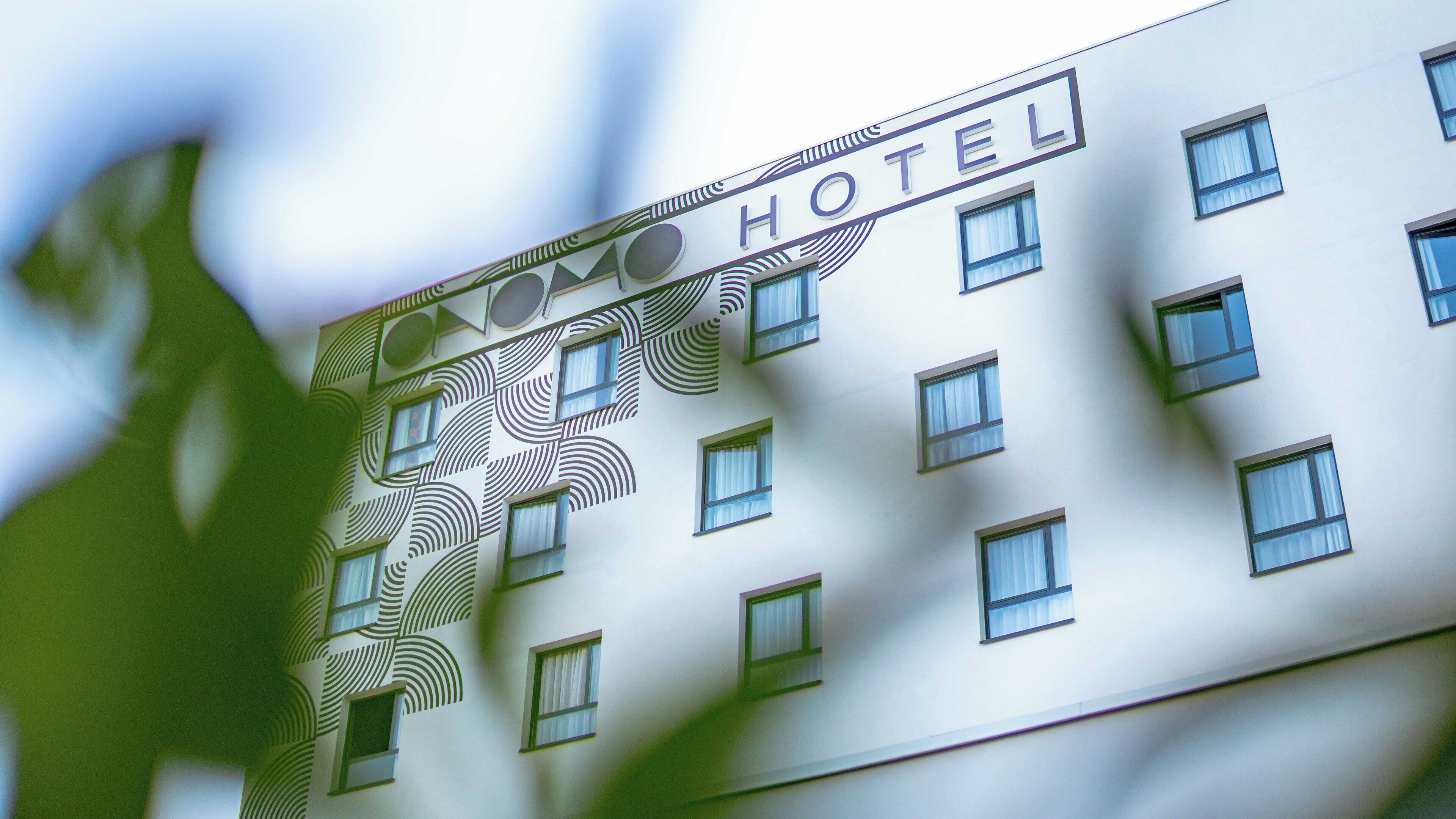 Un bâtiment d’hôtel doté d’une façade moderne, de nombreuses fenêtres et d’une enseigne indiquant qu’il s’agit d’un hôtel.