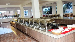 Un'impostazione buffet con diverse postazioni cibo, un pavimento in marmo e ampie finestre che lasciano entrare la luce naturale.