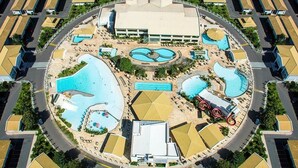 Vista aerea di un resort con diverse piscine, un edificio centrale e ville circostanti.