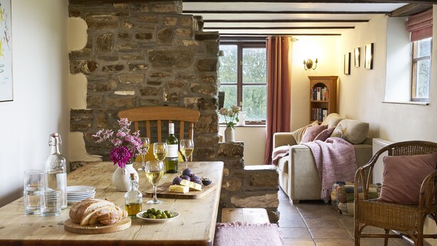 A rustic room with a stone wall, wooden furniture, and a cozy seating area. - Barn Conversion With Indoor Swimming Pool In Stunning Rural Location Near Ocean (Bude)
