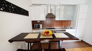 Una cocina moderna con gabinetes blancos, un microondas, una estufa y un frutero sobre la encimera.