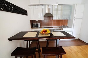 Cozinha moderna com armários brancos, micro-ondas, fogão e uma fruteira sobre o balcão.