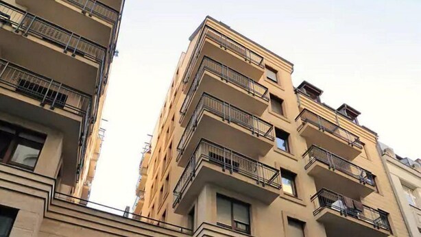 Un edificio de varios pisos con balcones, un coche negro estacionado adelante y un letrero que dice "MUSC".