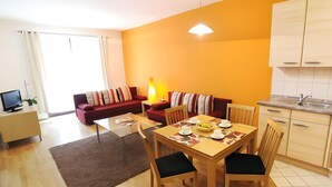 Ein modernes Wohnzimmer mit Sofa, Couchtisch, Esstisch und Küchenbereich.