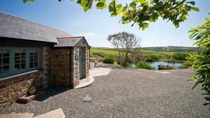 A stone building with a gravel driveway leading to a pond. - Luxury Cottage With Indoor Swimming Pool In Stunning Rural Location Near Ocean (Bude)