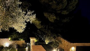 A nighttime view of a swimming pool area with stone steps leading up to the pool, surrounded by greenery and stone walls. - Villa with pool in Maussane les Alpilles, incredible view of the valley (Maussane-les-Alpilles)