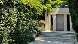 A stone staircase leading to a building with a wooden door, surrounded by lush greenery and trees. - Villa with pool in Maussane les Alpilles, incredible view of the valley (Maussane-les-Alpilles)