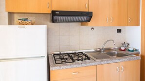 Une cuisine dotée de meubles en bois, d’une cuisinière à gaz, d’un four encastré et d’un évier en acier inoxydable.