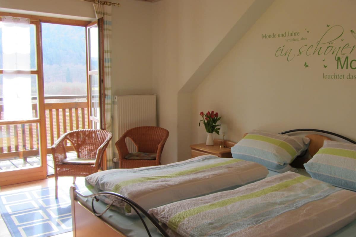 A bedroom with a bed, a chair, a nightstand, and a wall decoration.