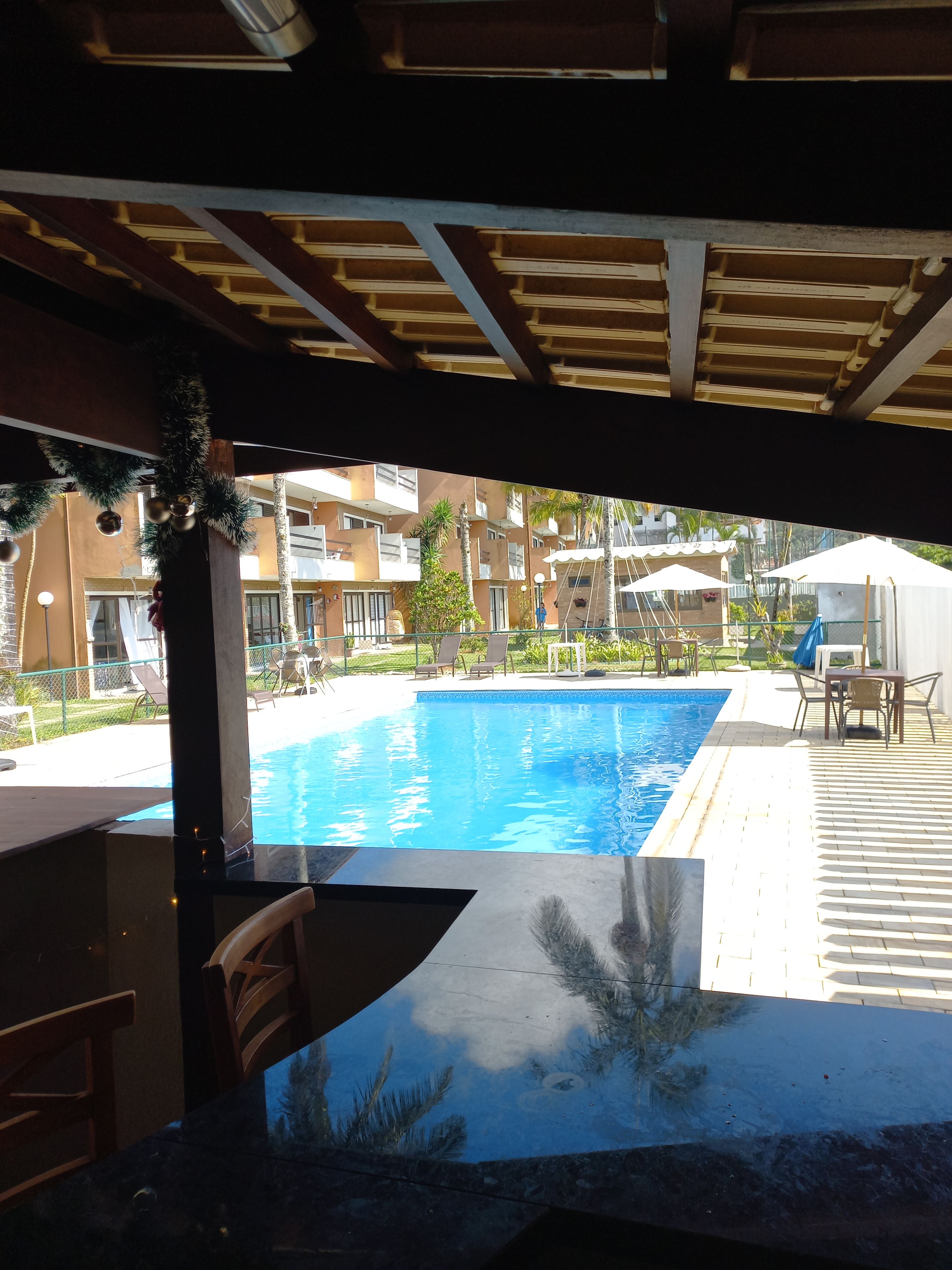 Une piscine dotée d’une terrasse carrelée, de chaises longues et d’un espace salon abrité.
