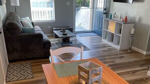 Una sala moderna con una mesa de comedor de madera, un sofá y un televisor montado en la pared.