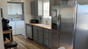 Una cocina funcional con un refrigerador de acero inoxidable, lavadora y microondas.