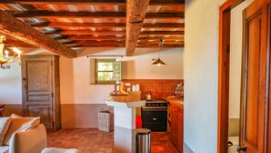 A rustic kitchen with exposed wooden beams, a vintage stove, and a small window. - Casa Sarralonga Di Porto-Vecchio (Porto-Vecchio)