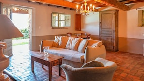 A cozy living room with a wooden ceiling, a chandelier, a sofa, a coffee table, and a dining area with a table and chairs. - Casa Sarralonga Di Porto-Vecchio (Porto-Vecchio)