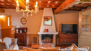A cozy living room with a fireplace, a television, and a chandelier. - Casa Sarralonga Di Porto-Vecchio (Porto-Vecchio)