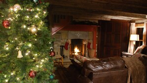 A cozy living room with a Christmas tree, leather sofa, and a fireplace.